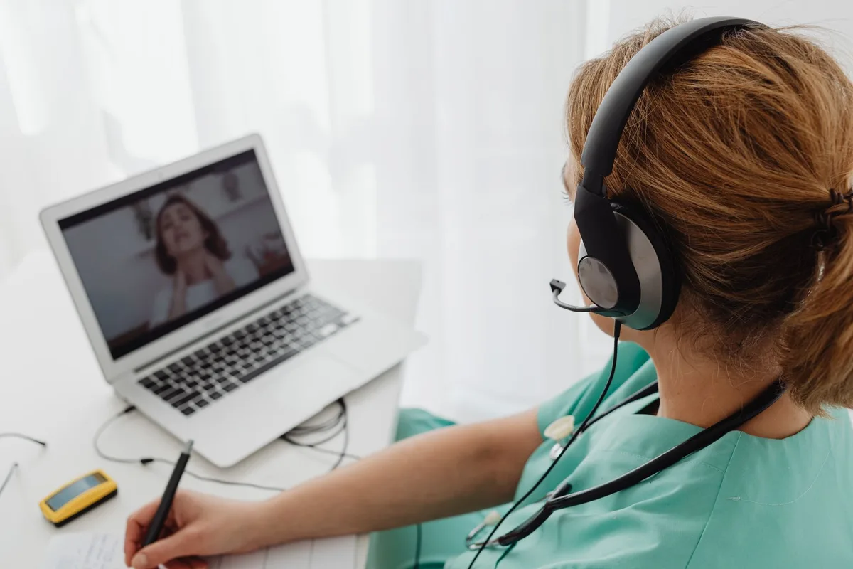 Personne en consultation par appel vidéo avec un praticien, interface de chat visible
