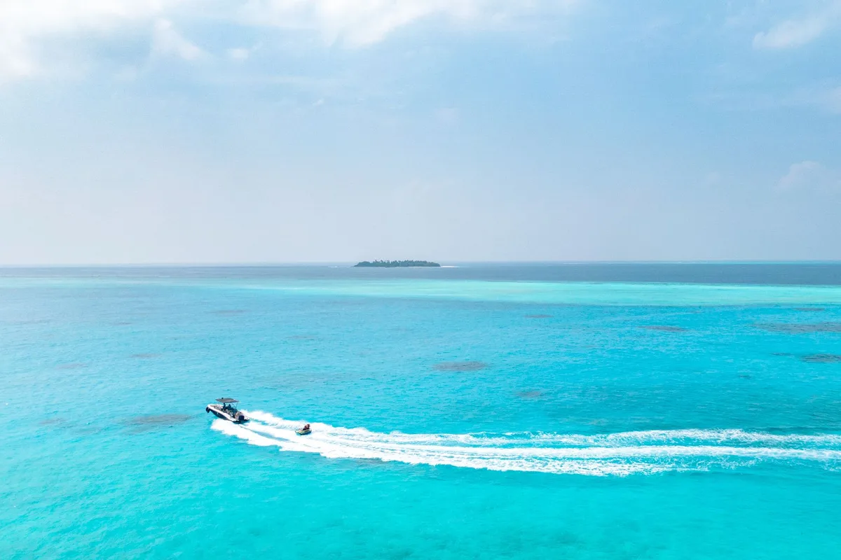 Un bateau rapide traversant les eaux turquoise vers une île tropicale