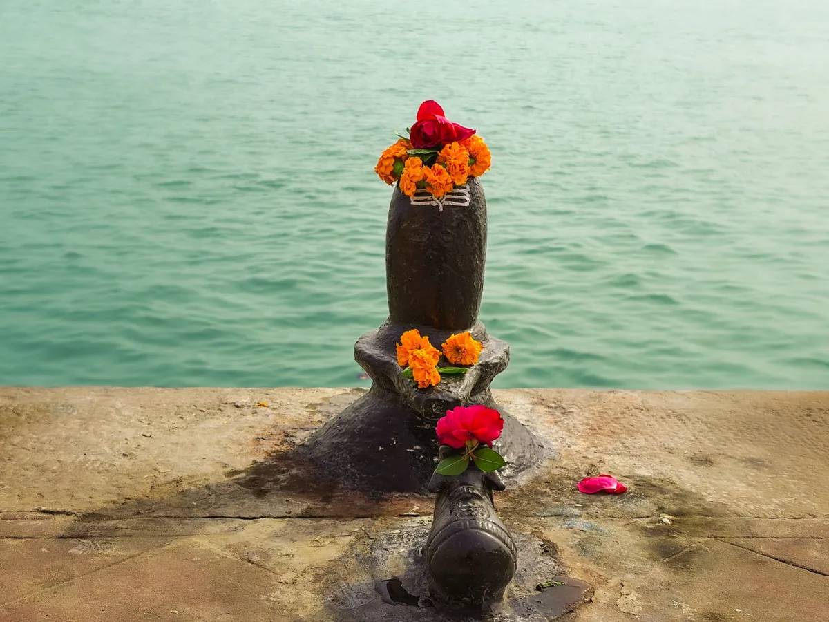 Mains versant de l'eau et du lait sur un lingam lors d'une puja Sawan
