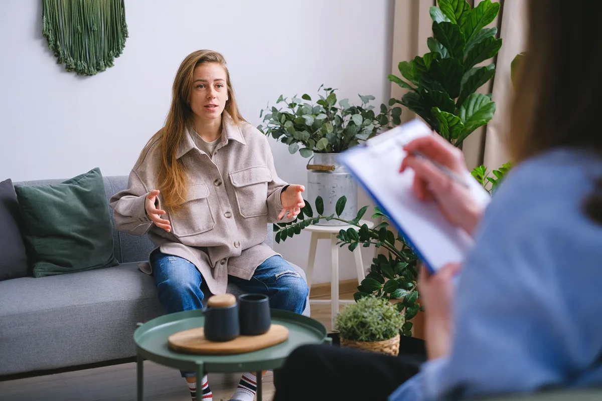 Une femme en séance de thérapie cognitivo-comportementale avec un thérapeute dans un bureau calme