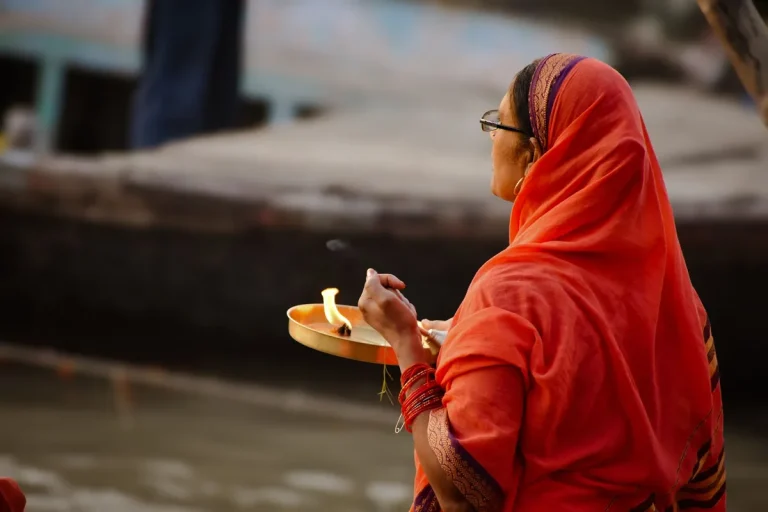 Femme en prière devant un autel, mains jointes, fleurs vertes et offrandes rituelles visibles