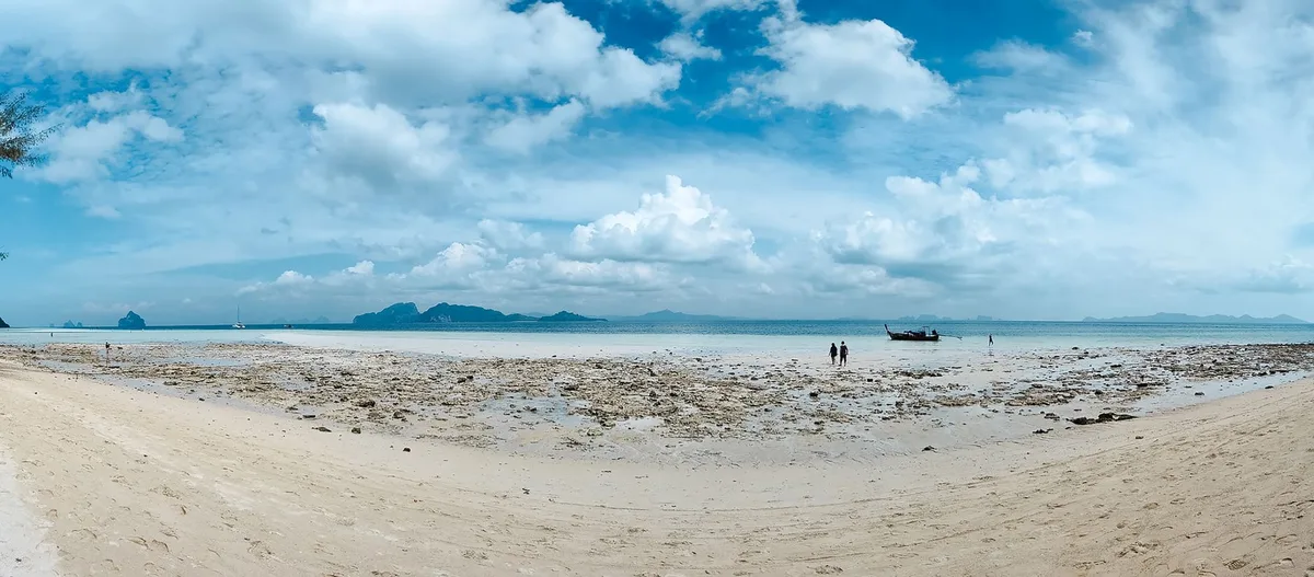 Longue bande de sable blanc immergée à marée basse entre les îles