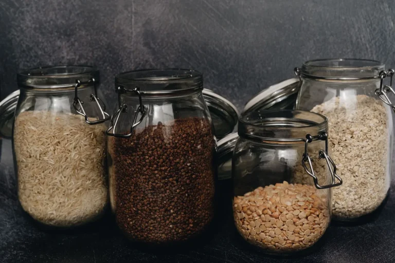 Des mains anonymes triant des céréales complètes dans une cuisine, avec une loupe pour inspecter les grains
