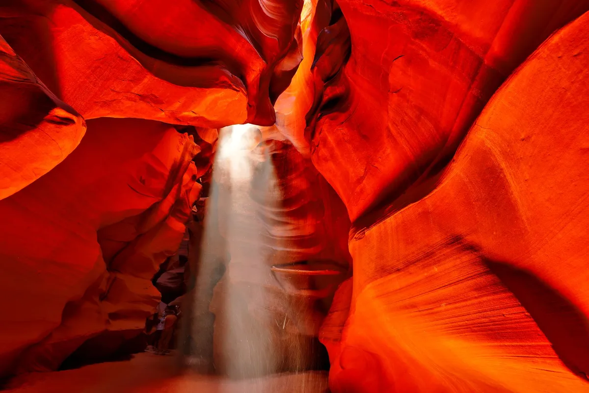 Faisceaux de lumière dorée traversant les parois étroites d'un canyon de pierre rouge