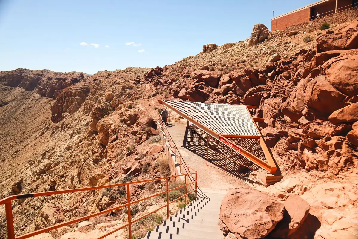 Escaliers métalliques dans un paysage désertique rocheux avec visiteurs en descente