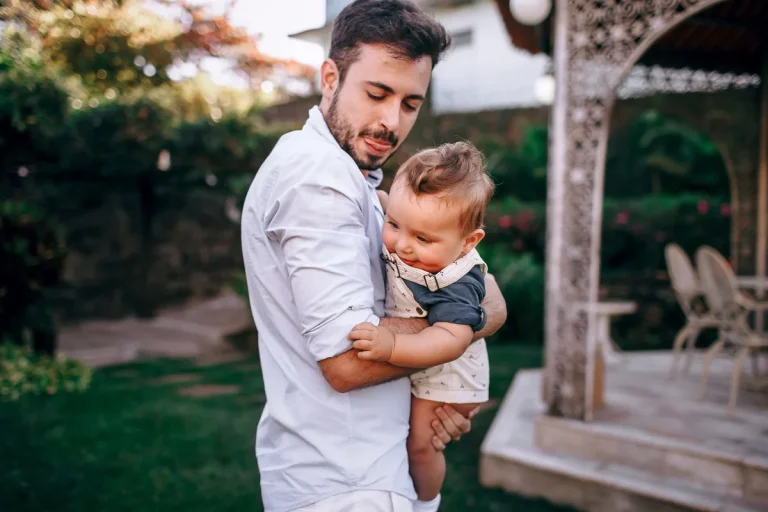Parent et enfant assis ensemble dans un moment de calme, se touchant doucement, lumière naturelle douce.