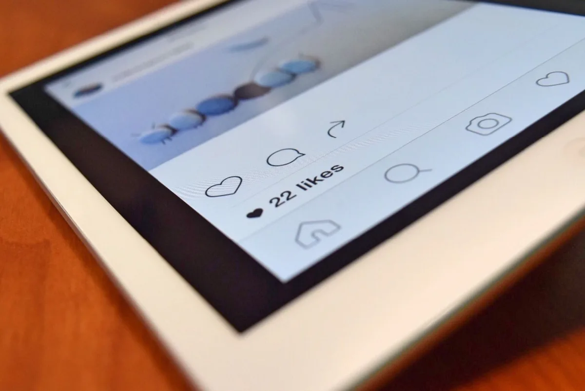 Mains tenant un téléphone avec des icônes de validation et de likes visibles