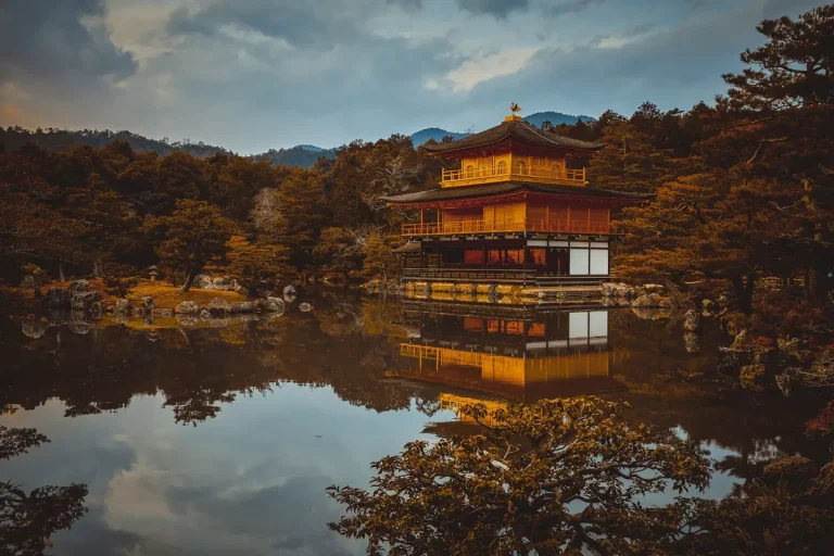 Jardin de temple traditionnel avec pagode reflétée dans l'eau et feuillage automnal
