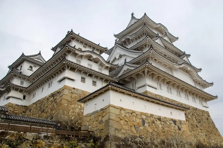 Château blanc médiéval japonais avec ses remparts et ses portes fortifiées, vu de la distance