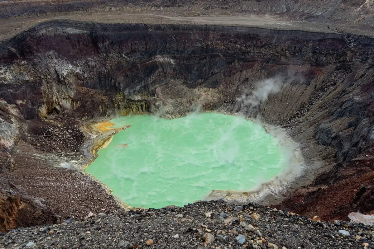 Paysage volcanique avec lac acide entouré de formations minérales jaunes