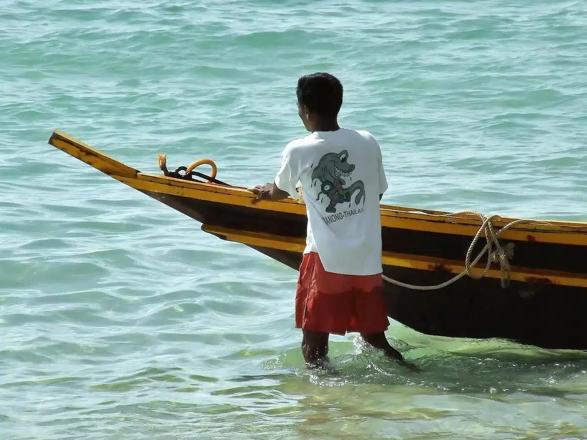 Bateau longtail traditionnel traversant une baie avec falaises karstiques