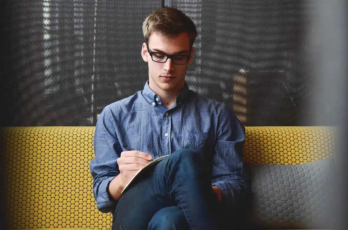 Main écrivant une petite intention sur un carnet posé sur un bureau lumineux