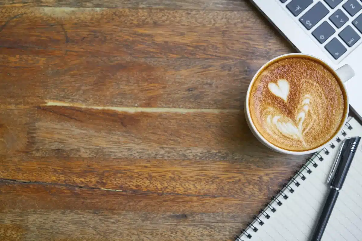 Petit carnet posé visible sur une table près d'une tasse de café